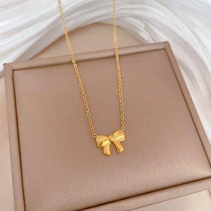 Close-up of golden bow pendant on an O-chain over elegant white silk fabric