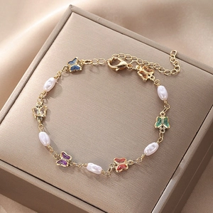 Detail of a gold bracelet with colorful enamel butterflies and baroque pearls on silk
