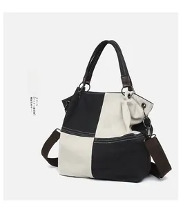 Detail of contrast canvas tote showing side capacity, brown handle and metal buckle