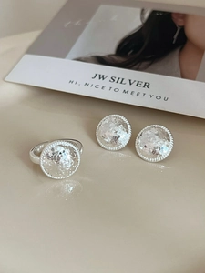 Close-up of silver hammered earrings and open ring set with elegant beaded edges