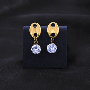 Gold coffee bean earrings with round zircon stones on black textured background