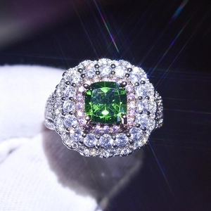 Macro shot of a square emerald ring with sparkling halo diamonds on a dark background