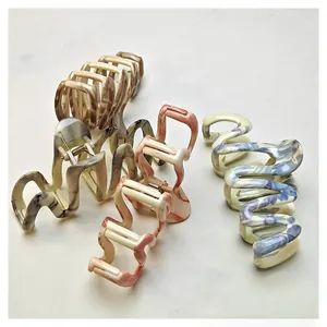 Detail of four acetate hair claws featuring marble and tortoiseshell patterns in S-curve design