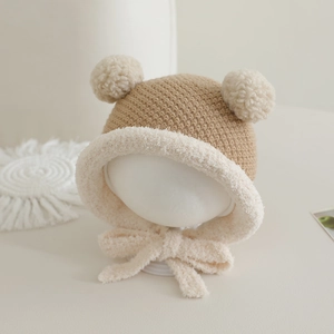 Detail der Baby-Strickmütze mit zwei Bommeln, Plüschrand und Bindebändern in Khaki