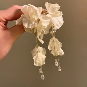Detail shot of elegant white jasmine flower tassel earrings with golden chains and beads.