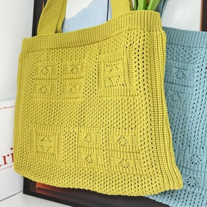 Detailed view of yellow-green and light blue knitted tote bags with hollow patterns