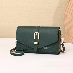 Detail of dark green leather crossbody bag with golden horseshoe buckle and textured finish