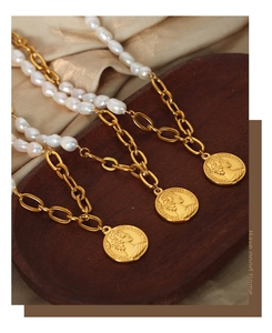 Detailed close-up of vintage gold coin pendants and freshwater pearls on silk fabric