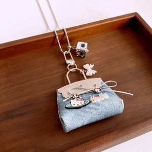 Detailed close-up of a blue denim cat bag pendant with silver chain and bow