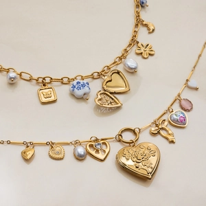 Détail de collier doré vintage avec médaillon coeur, relief de rose et perles en céramique