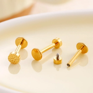 Golden titanium flat disc cartilage earrings with textured surface and screw thread details