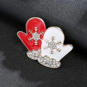 Detailed close-up of a festive red mitten brooch with white rhinestones and snowflake patterns