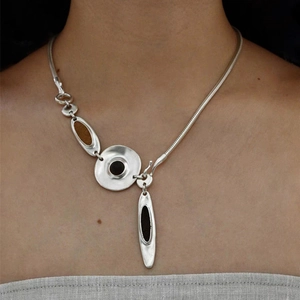 Detail of an irregular metal necklace with dark resin inlay on a snake chain