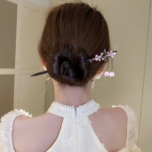 Elegant back view of hair bun styled with a purple flower hair stick and tassel