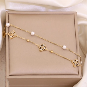 Close-up of gold titanium bracelet with white pearls and crystal flower pendant on jewelry box