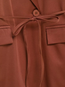 Detail of rust brown blazer featuring twill fabric texture with button and waist tie