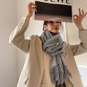 Elegant grey cashmere-like scarf with fringe detail worn with a stylish beige blazer