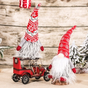 Gnomes de Noël avec chapeaux à flocons sur voiture vintage rouge et souche en bois