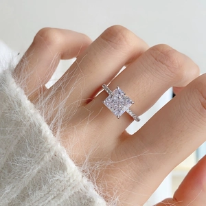 Close-up of square cut radiant diamond ring with pavé band on a model hand