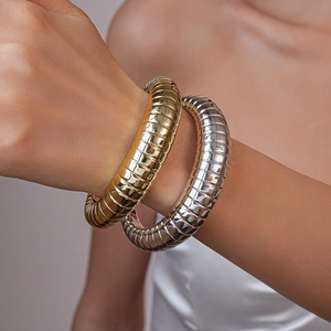 Close-up of gold and silver textured ribbed metal bangles on a female model wrist