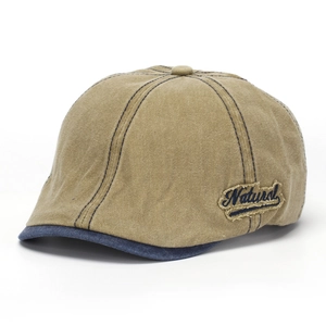 Side view detail of a vintage washed denim flat cap featuring 'Natural' embroidered patch.