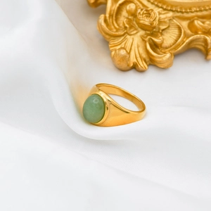 Detail of 18k gold plated ring featuring a green oval stone on white silk background