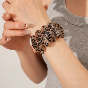 Detailed close-up of a wide leopard print resin bangle worn on a model's wrist