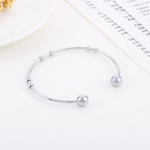 Macro view of minimalist C-shaped stainless steel cuff bracelet with polished silver beads