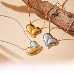 Three minimalist heart pendant necklaces in gold and silver finish on wooden decor