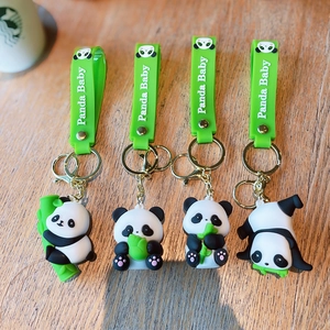 Set of four cute cartoon panda keychains with bamboo and green wrist straps on wood