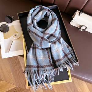 Detail of a light blue plaid scarf with fringes displayed on a tray with accessories