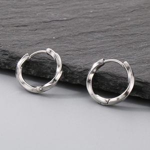 Macro shot of silver Mobius twist hoop earrings on dark stone background texture