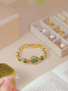 Detail shot of a gold women's watch with green gems and a matching green dial