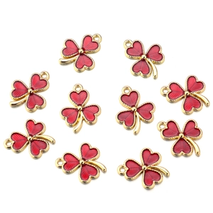 Macro detail of red enamel heart clover charms with gold plating for DIY jewelry making