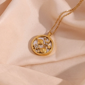 Detail of a gold celestial necklace with star and moon charms on champagne silk