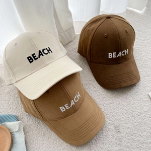 Three earth-tone cotton baseball caps with BEACH 3D embroidery on a soft rug