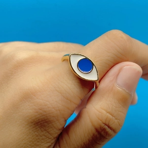 Close-up of fashion gold evil eye ring with blue enamel detail on a model finger
