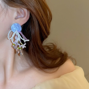 Close-up of beaded tassel earrings with purple studs and teardrop accents on a model