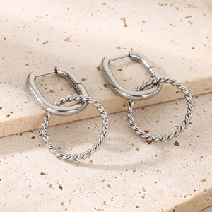 Detail view of silver twisted hoop earrings with a U-shaped buckle on beige stone