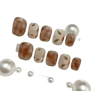 Handmade amber marble and floral press-on nails with golden edges on white background