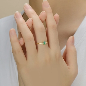 Bague élégante en argent S925 doré avec tourmaline verte sur la main d'un mannequin