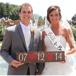 Close-up of white Bride to Be sash and custom date wooden sign for bachelorette parties
