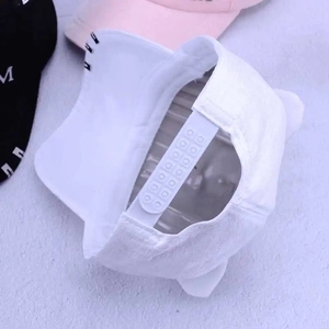 Detailed view of the adjustable plastic snap closure on a white cat ear baseball cap