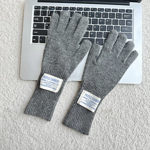 Detail of grey knitted wool gloves with ribbed cuffs and stitched textile label