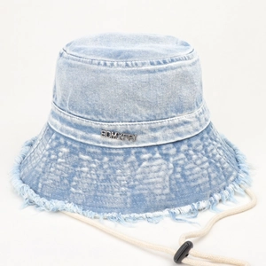 Dettaglio del cappello alla pescatora in denim lavato azzurro con bordi sfrangiati e logo