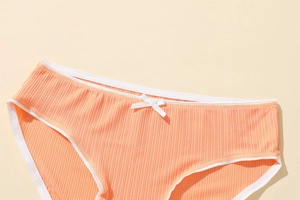 Detail of skin-toned women's briefs with vertical rib texture and white ribbon bow