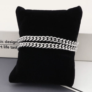Gros plan d'un bracelet gourmette en acier inoxydable argenté sur un présentoir en velours