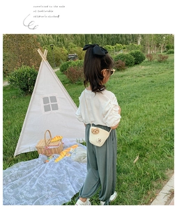 Dettaglio di una borsa a tracolla intrecciata beige per bambini con gatto decorativo