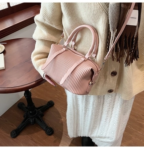 Detail of pink pleated Boston bag with leather handles and adjustable shoulder strap