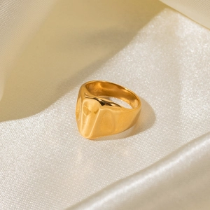 Gros plan d'une bague en acier inoxydable plaqué or 18 carats sur du satin champagne